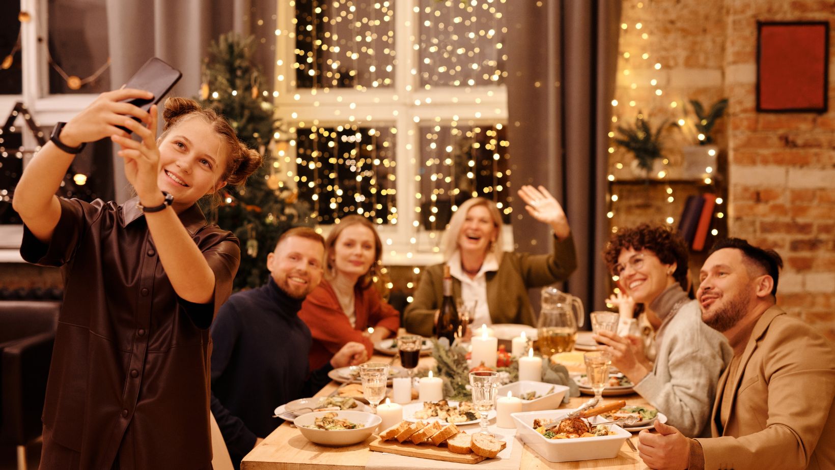 Someone taking a selfie at a festive dinner table with fellow employees at a work Christmas party